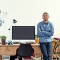 He brings designs to life. Portrait of a casually-dressed young man sitting on his desk in an office. Royalty Free Stock Photo