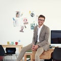 I absolutely love my job. Portrait of a casually-dressed young man sitting on his desk in an office. Royalty Free Stock Photo