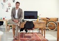 Office trends. Portrait of a casually-dressed young man sitting on his desk in an office. Royalty Free Stock Photo