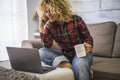 Portrait of caucasian adult beautiful woman at home use a laptop computer sitting on the couch - concept of video call conference