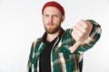 Portrait of caucasian bearded man wearing hat and plaid shirt showing thumb down, while standing isolated over white background Royalty Free Stock Photo