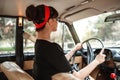 Portrait of Caucasian beautiful young girl in black vintage dress and vintage glasses posing behind the wheel of a vintage car Royalty Free Stock Photo