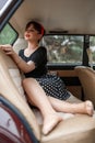 Portrait of a Caucasian beautiful young girl in a black vintage dress, posing in the cabin of a vintage car Royalty Free Stock Photo