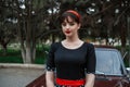 Portrait of a Caucasian beautiful young girl in a black vintage dress, posing near a vintage car Royalty Free Stock Photo