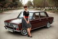 Portrait of a Caucasian beautiful young girl in a black vintage dress, posing near a vintage car Royalty Free Stock Photo