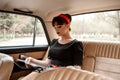 Portrait of a Caucasian beautiful young girl in a black vintage dress, posing in the salon of vintage car reading an old magazine Royalty Free Stock Photo