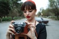 Portrait of Caucasian beautiful young girl in black vintage dress posing with vintage camera in hands Royalty Free Stock Photo