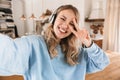 Portrait of caucasian blond girl 20s wearing headphones smiling and taking selfie photo at home Royalty Free Stock Photo