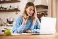 Portrait of caucasian blond woman 20s wearing casual sweatshirt working on laptop and writing down notes at home Royalty Free Stock Photo