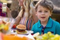 Portrait of caucasian boy sitting with family at table in the garden during lunch Royalty Free Stock Photo