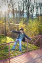 Portrait of caucasian boy in warm clothes playing and balancing on railing of the bridge in autumn park Royalty Free Stock Photo