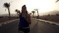 Portrait of caucasian brunette girl jogging at tropical highway at sunrise.