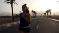 Portrait of caucasian brunette girl jogging at tropical highway at sunrise.