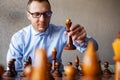 Caucasian businessman playing chess at table reaching king piece for concept about overcoming difficulty and achieving goals.