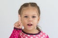 Portrait of caucasian child of three years old holding finger to show number one or telling importance looking at camera on the