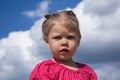 Portrait of caucasian child of two years looking aside with serious look with interest on the blue sky with clouds