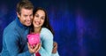 Portrait of a caucasian couple holding a piggy bank against copy space on textured blue background Royalty Free Stock Photo