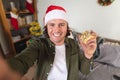 Portrait of caucasian disabled man wearing a santa hat holding christmas gift at home