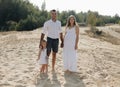 Portrait of caucasian family with baby in white clothes are standing on sands dune. Pregnant mpther. Newborn Royalty Free Stock Photo