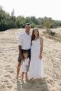 Portrait of caucasian family with baby in white clothes are standing on sands dune. Pregnant mpther. Newborn Royalty Free Stock Photo