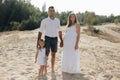 Portrait of caucasian family with baby in white clothes are standing on sands dune. Pregnant mpther. Newborn Royalty Free Stock Photo