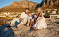 Portrait of a caucasian family watching the sunset sitting on a rock together on the beach. Parents spending time with Royalty Free Stock Photo