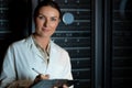 Portrait of caucasian female engineer wearing an apron writing on clipboard in computer server room Royalty Free Stock Photo