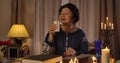 Portrait of Caucasian female magician blowing out candle and putting it on the table. Smiling mature woman performing