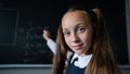 Portrait of a caucasian girl in the classroom. The schoolgirl writes the formula with chalk on the blackboard and looks Royalty Free Stock Photo