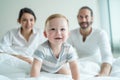Portrait of Caucasian happy family smiling, look at camera in bedroom. Young attractive couple parents, father and mother sit on Royalty Free Stock Photo