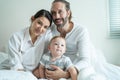 Portrait of Caucasian happy family smiling, look at camera in bedroom. Young attractive couple parents, father and mother sit on Royalty Free Stock Photo