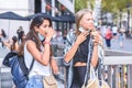 Portrait of caucasian and indian female friends drinking take away coffee near underground entrance in street Royalty Free Stock Photo