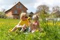 Portrait of Caucasian little children on the dandelion field with flowers in hands. Blonde boy and girl sits in the grass on house Royalty Free Stock Photo