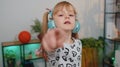 Happy child girl kid in headphones dancing and jumping while listening to the music at home alone Royalty Free Stock Photo