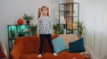 Happy child girl kid wears earphones dancing and jumping while listening to the music at home alone Royalty Free Stock Photo