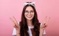 Portrait of Caucasian long-haired brunette hipster in a bandana and glasses and shows emotion on a pink background Royalty Free Stock Photo