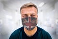 Portrait of caucasian male, health professional, millennial, in dirty medical surgeon face mask with a UK flag on it and shirt Royalty Free Stock Photo