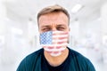 Portrait of caucasian male, health professional, millennial, in medical surgeon face mask with USA flag on it and sweaty short. Co Royalty Free Stock Photo