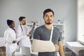 Portrait of caucasian man with bandage on broken hand standing in hospital ward