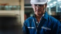 Portrait of caucasian man industrial worker or labor in blue factory uniform with white safty helmet in factory metal workshop Royalty Free Stock Photo