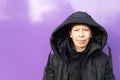 Portrait of a Caucasian middle-aged woman in a black coat on a purple background Royalty Free Stock Photo