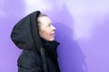 Portrait of a Caucasian middle-aged woman in a black coat on a purple background Royalty Free Stock Photo