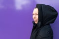 Portrait of a Caucasian middle-aged woman in a black coat on a purple background Royalty Free Stock Photo