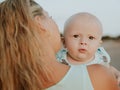 Portrait of Caucasian mother with blond hair and baby son spending time on beach. Mom holding infant boy. Summer vacation. Family Royalty Free Stock Photo