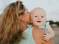 Portrait of Caucasian mother with blond hair and baby son spending time on beach. Mom holding infant boy. Summer vacation. Family Royalty Free Stock Photo