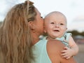 Portrait of Caucasian mother with blond hair and baby son spending time on beach. Mom holding infant boy. Summer vacation. Family Royalty Free Stock Photo