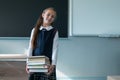 Portrait of a caucasian schoolgirl with a backpack. The girl is holding a stack of textbooks in the classroom.