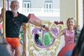 Portrait of Caucasian senior couple man and woman smile and holding hands while ride horse on Carousel at amusement park with happ