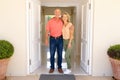 Portrait of caucasian senior couple smiling while standing on the front door of their house Royalty Free Stock Photo