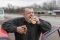 Caucasian senior driver gobbling lyulya kebab in lavash near his car